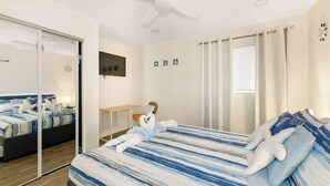 A hotel room with a bed, a desk, a chair, a ceiling fan, and a large mirror. - Heated Pool No Extra Fee ! firepit| Game Room (Palm Coast)