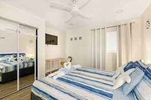 Ein Hotelzimmer mit einem Bett, einem Schreibtisch, einem Stuhl, einem Deckenventilator und einem großen Spiegel.