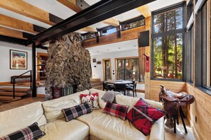A spacious living area with a stone wall centerpiece, a leather sofa with patterned cushions, and a dining area with a wooden table and chairs. - NEW! Magical home in prime neighborhood (Breckenridge)
