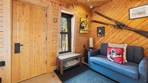 En inredning med träpanel, en soffa, en bänk, ett fönster och en vägglampa.