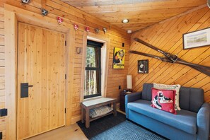 A wooden interior with a sofa, a bench, a window, and a wall-mounted lamp. - NEW lodging experience like no other (Breckenridge)