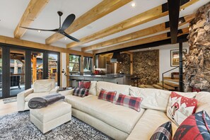 A spacious living area with a high ceiling, a built-in kitchen, and a stone accent wall. - NEW lodging experience like no other (Breckenridge)