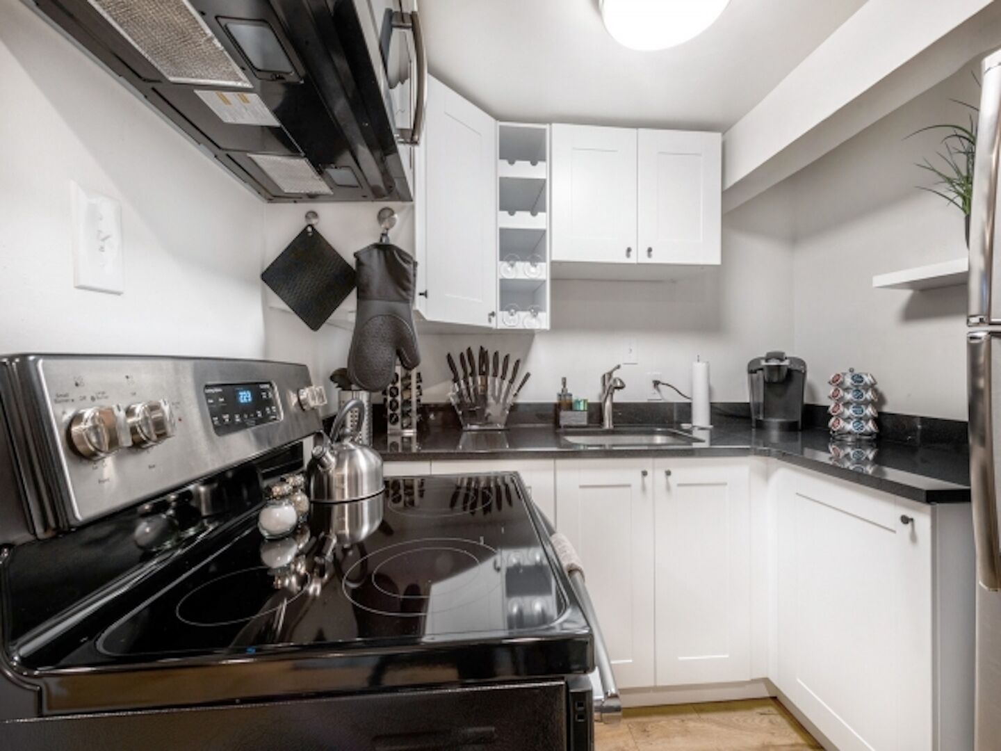 A modern kitchen with a black stove, white cabinets, and a stainless steel sink.