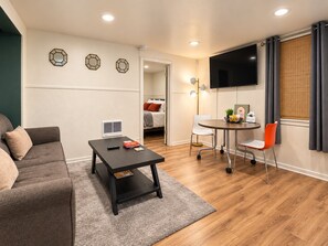 Ein modernes Wohnzimmer mit einer Couch, einem Couchtisch, einem Fernseher und einem Essbereich mit Stühlen.