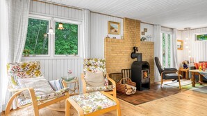 Ein gemütliches Wohnzimmer mit Kamin, Holzmöbeln und großen Fenstern.