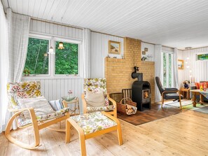Ein gemütliches Wohnzimmer mit Kamin, Holzmöbeln und großen Fenstern.