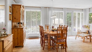 Ein Essbereich mit Holztisch und -stühlen, einem Schrank und einem Fenster mit Vorhängen.