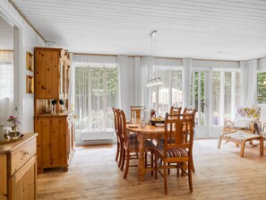 Ein Essbereich mit Holztisch und -stühlen, einem Schrank und einem Fenster mit Vorhängen.