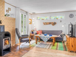 A cozy living room with a fireplace, a sofa, a dining table, and a TV. - "Frerich" - 450m to the fjord by Interhome (Løgstør)