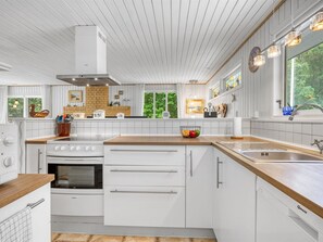 Eine moderne Küche mit weißen Schränken, einer Holz Arbeitsplatte und einem großen Fenster.