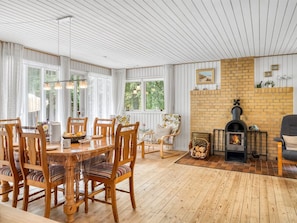 A dining area with wooden chairs and a table, a fireplace with a brick surround, and large windows with curtains. - "Frerich" - 450m to the fjord by Interhome (Løgstør)