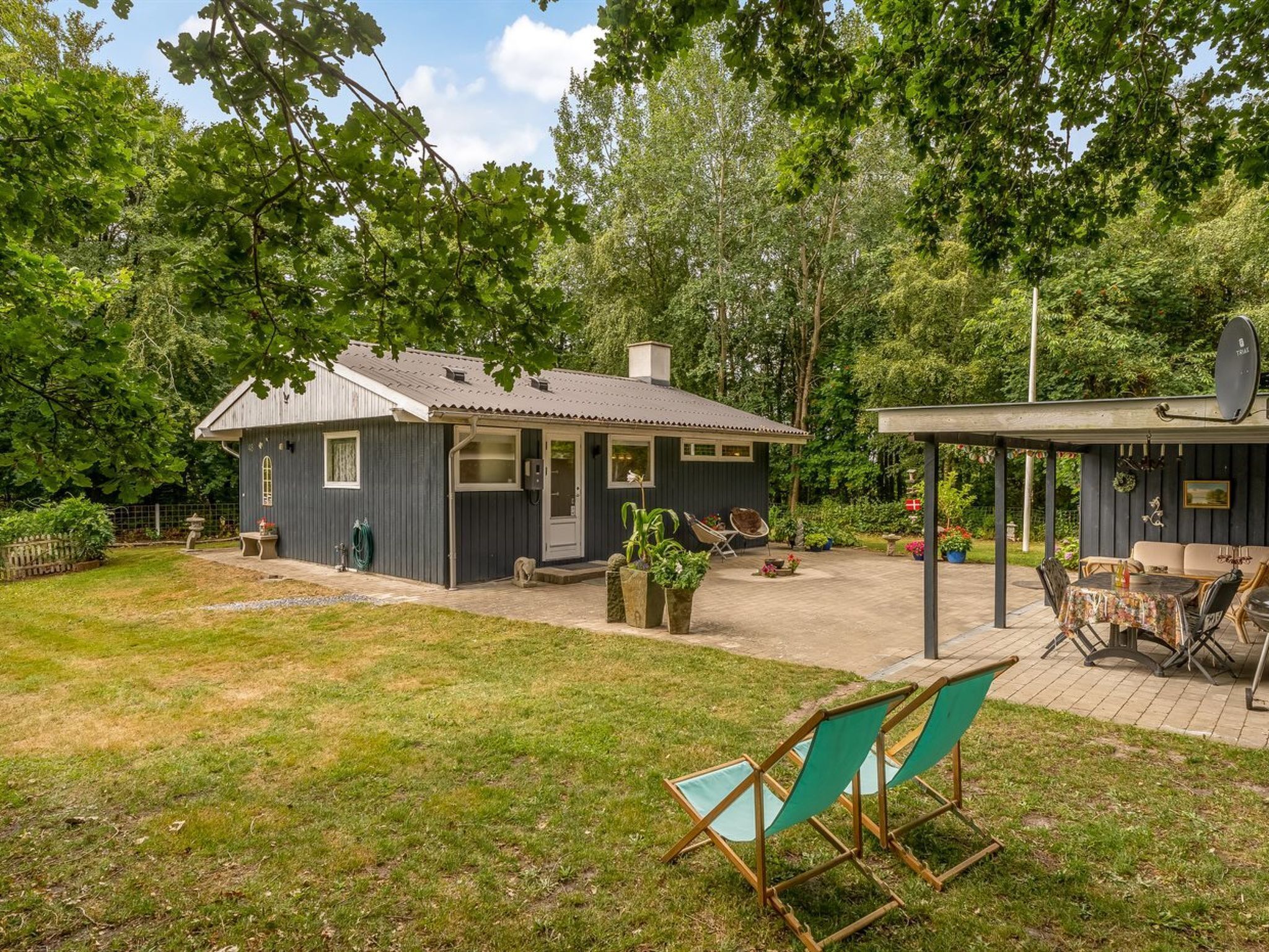 A house with a covered patio, a fenced yard, and a satellite dish.