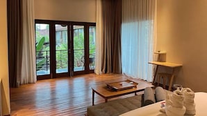 Habitación de hotel con un amplio ventanal corredero que da a un balcón, un ventilador de techo, una mesa de madera y una cama con toallas.