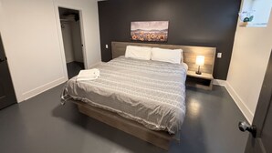 Un dormitorio con cama, mesita de noche, un cuadro y una ventana.