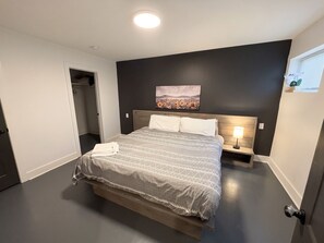 A bedroom with a bed, a nightstand, a painting, and a window. - Nashville 1BR • Private Entrance • King Bed (Nashville)