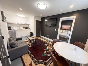 A compact living space with a kitchenette, a sofa, a dining table, and a TV mounted on the wall. - Nashville 1BR • Private Entrance • King Bed (Nashville)