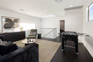 A modern living room with a sofa, coffee table, and a foosball table. - Reign by Khove (Paradise Point)