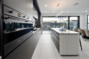 A modern kitchen with a central island, built-in appliances, and a view to the outdoor area.