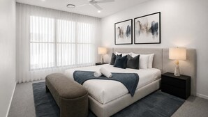 Ein modernes Schlafzimmer mit einem Bett, Nachttischen, einer Bank und Kunstwerken an der Wand.