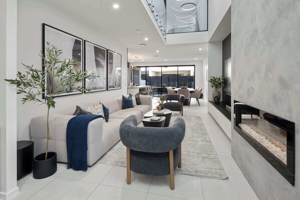 A modern living room with a sofa, armchairs, a coffee table, and a fireplace.