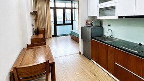 Una cocina moderna con armarios blancos, un microondas integrado y un lavamanos de acero inoxidable.