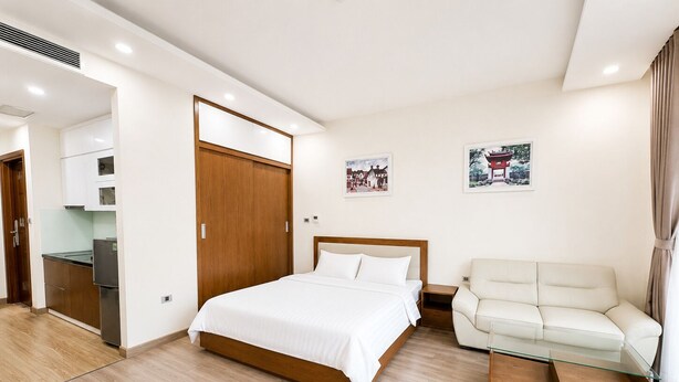 Una habitación de hotel moderna con una cama, un sofá, una mesa de centro de vidrio y una kitchenette.