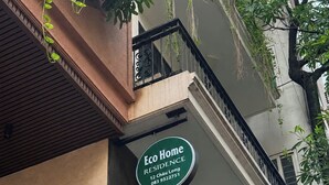 Un edificio con un cartel verde que indica Eco Home Residence, e incluye un número de contacto.