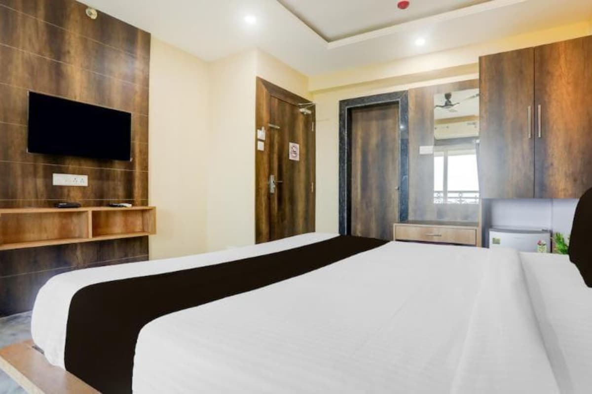 Ett hotellrum med en stor säng, en platt-TV som är monterad på väggen, trägarderober och en liten sittgrupp med ett bord och stolar.