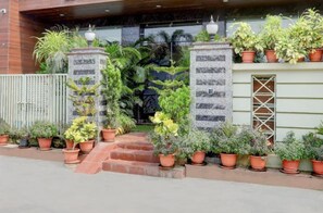 Entrada de un edificio con fachada de piedra, puerta de madera y varios maceteros colocados al frente.