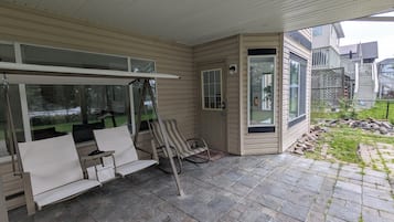 En inglasad veranda med en sittgrupp, en dörr med ett fönster och utsikt över trädgården.