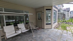 En inglasad veranda med en sittgrupp, en dörr med ett fönster och utsikt över trädgården.