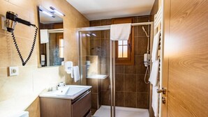 Een moderne badkamer met een douchecabine van glas, een wastafelmeubel en een handdoek aan de deur.