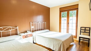 Een hotelkamer met twee bedden, een houten vloer, een raam met uitzicht en een stoel.