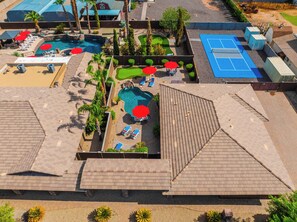 An aerial view of a resort with multiple swimming pools, sun loungers, and a tennis court. - "The Ultimate" 1.3 Acre! Guesthouse & Massive Pool! Pickleball & Putting Greens! (Gilbert)