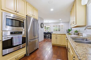 Una cucina moderna con elettrodomestici in acciaio inox, pavimento in legno e un'isola centrale con lavello.