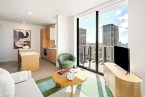 Ein modernes Wohnzimmer mit Sofa, Couchtisch, Fernseher und großem Fenster mit Blick auf die Stadt.