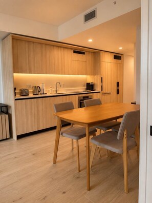Eine moderne Küche mit Holzausstattung, einer zentralen Kochinsel und einem Essbereich mit Holztisch und Stühlen.