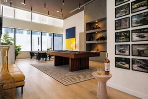Ein modernes Interieur mit Billardtisch, Sitzgelegenheit und Kunstwerken an den Wänden.