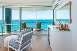 Une chambre avec vue sur l’océan, un climatiseur blanc et une table en bois avec de la verrerie.