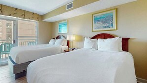 Quarto de hotel com duas camas, varanda com cadeiras e obras de arte nas paredes.