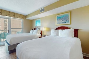 A hotel room with two beds, a balcony with chairs, and artwork on the walls. - Carolinian Beach Resort 0833 (Myrtle Beach)