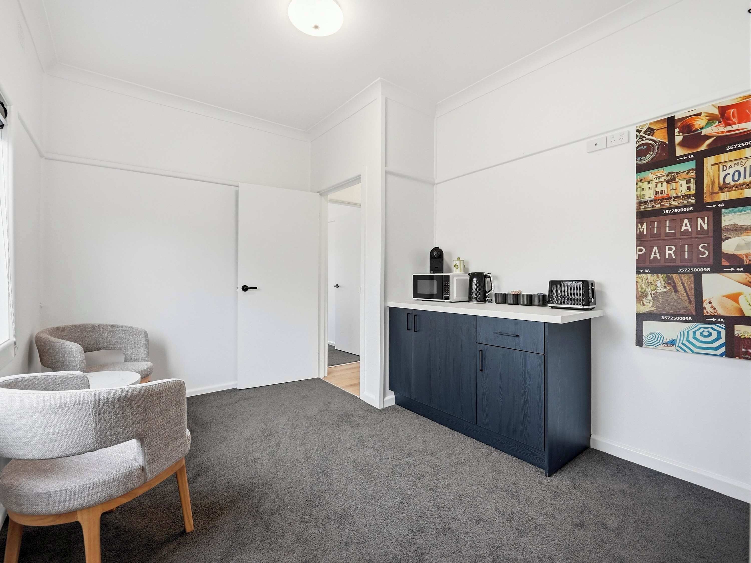 A small, modern kitchen with dark cabinets, a microwave, and a coffee maker.
