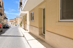 Eine schmale Stadtstraße mit Häusern an beiden Seiten, blauem Himmel und geparkten Autos.