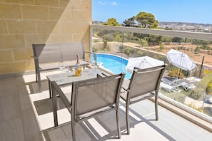 A balcony with a table and chairs, overlooking a swimming pool and a scenic landscape. - Pool And Sea - Modern Apart Sannat Gozo (Sannat)