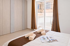 A hotel room with a bed, a magazine, and a view of the outside. - Pool And Sea - Modern Apart Sannat Gozo (Sannat)