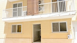 Ein zweistöckiges Wohngebäude mit Balkon, Tür und Fenstern.