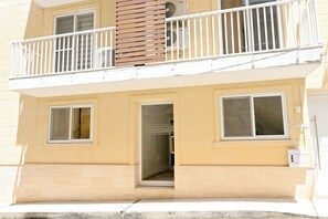 Ein zweistöckiges Wohngebäude mit Balkon, Tür und Fenstern.