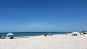 Ein Strand mit Menschen, Sonnenschirmen und Liegestühlen.