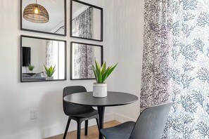 A dining area with a round table, two chairs, a potted plant, and a wall-mounted mirror. - Forever Sunshine - Fully Renovated (St. Petersburg)