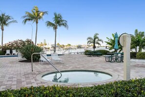 A pool area with lounge chairs, a hot tub, and palm trees. - Forever Sunshine - Fully Renovated (St. Petersburg)